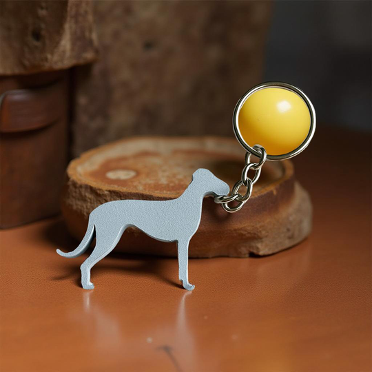 Dog-shaped keychain with a yellow ball on a wooden surface